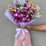 10 purple orchids in a pink and white wrap with white ribbon