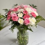 Shop the 'Brighten My Day' bouquet in Dubai – 10 white carnations, 10 pink carnations, 10 pink roses, and seasonal fillers in a glass vase. Same-day delivery available. Order now!