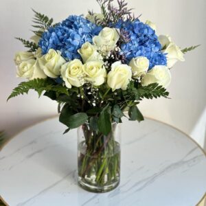 Deep Ocean flower arrangement with 20 white roses and 2 blue hydrangeas in a glass vase