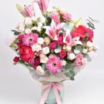 Spring Passion bouquet with pink lilies, white baby roses, pink roses, and pink gerberas wrapped in a pink ribbon