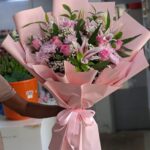 Lady Luck bouquet with pink lilies, pink roses, and purple chrysanthemums wrapped in pink paper